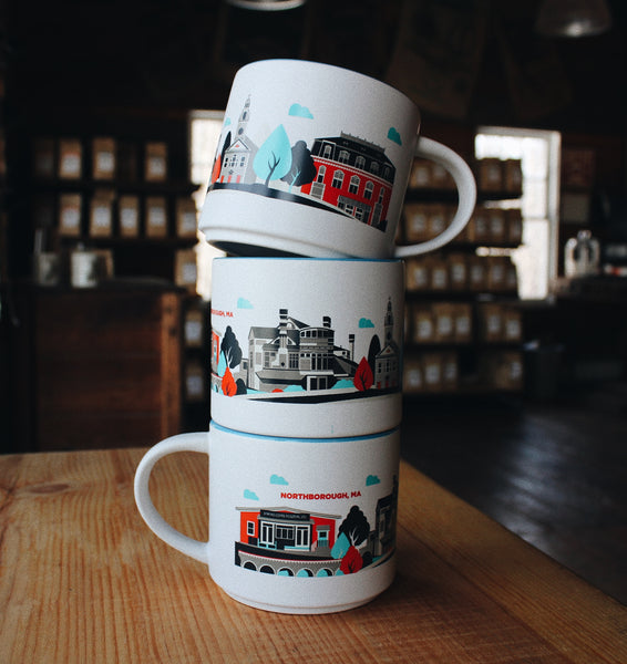 Stack of three mugs each with a white background and either a blue or red interior. Graphics that depict well known locations in Northborough wrap around the outside of the mug
