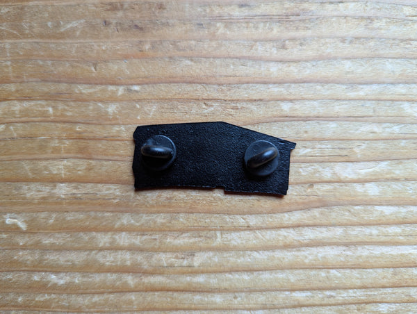 Back of The Mill enamel pin. Black metal with two black backings covering the sharp points of the pin.